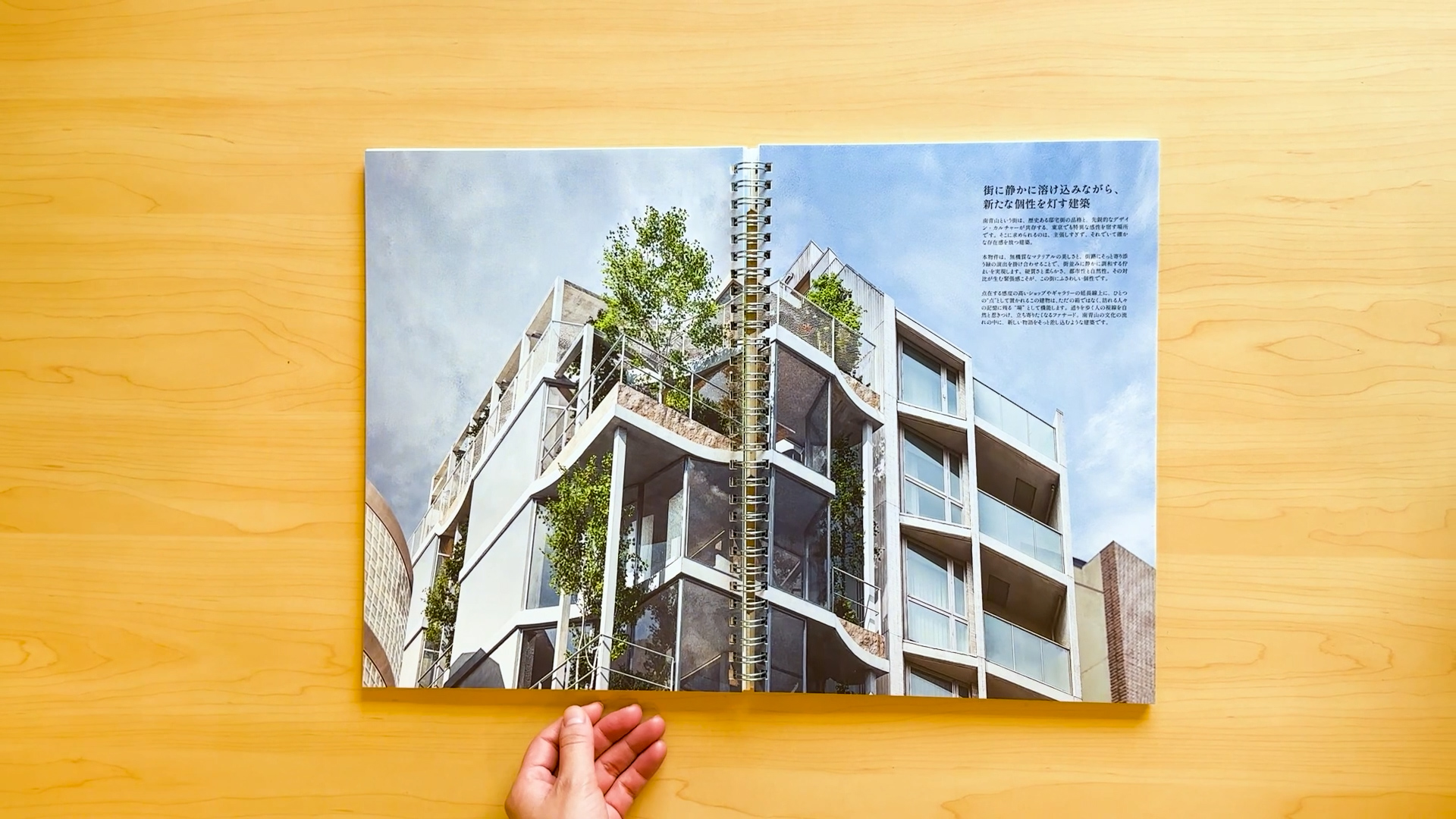 建物外観のCGパースを大胆に見開きで配置し、南青山のランドマークとしての存在感を伝えるページ